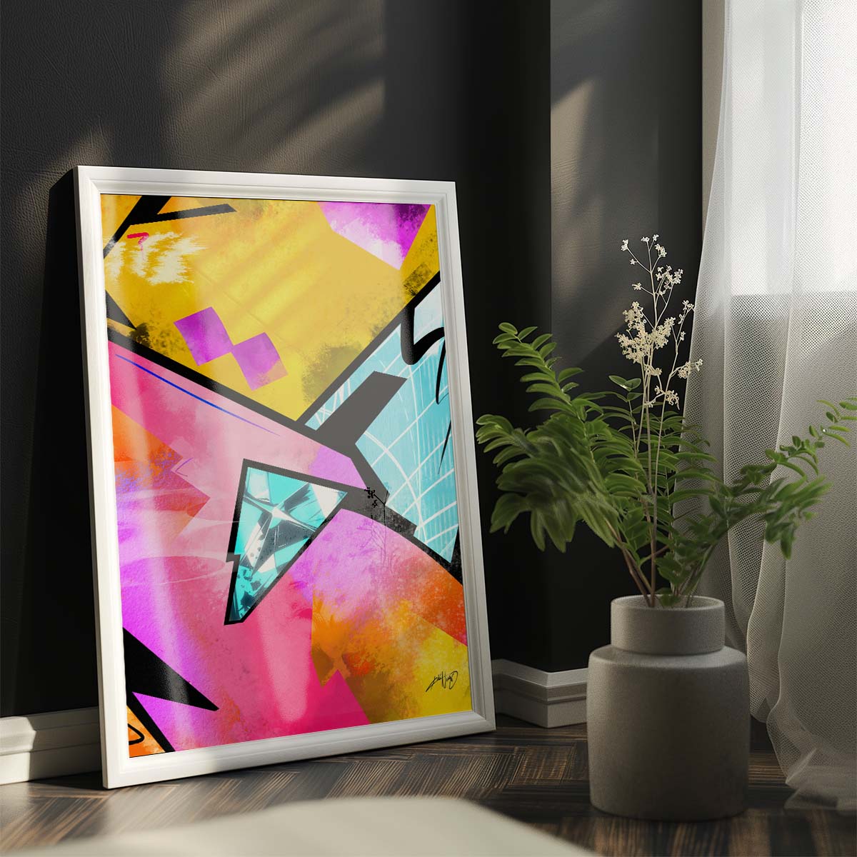 Three abstract paintings in yellow, pink, black, and blue colors with text elements hanging on the wall above a white bed with gray throw blanket and wooden nightstand with potted plant in a modern bedroom. Artwork by Kali Nuevo.