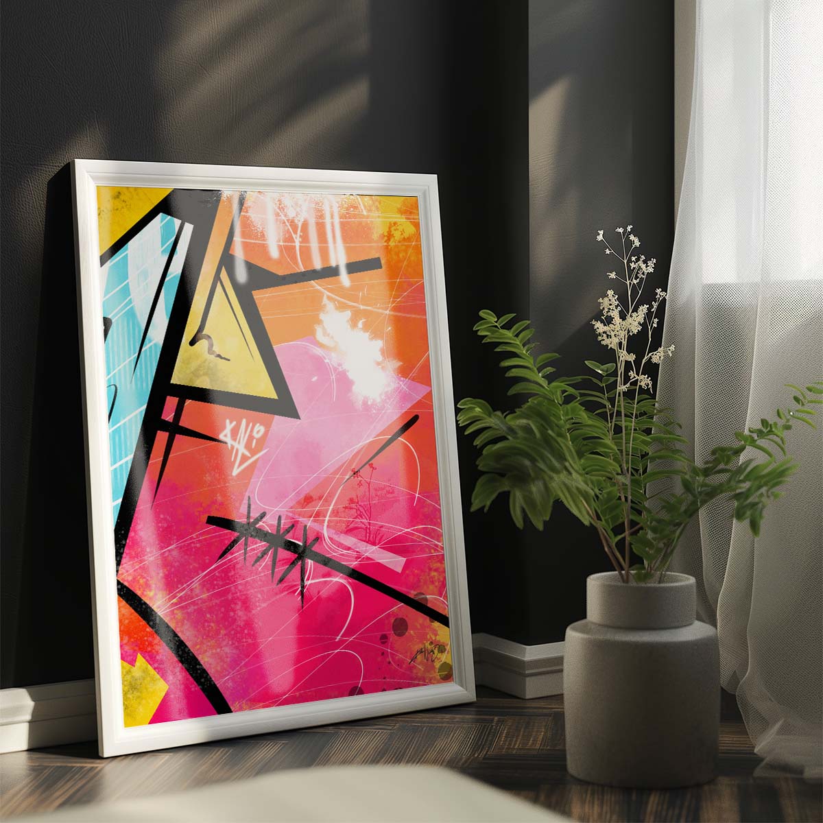 Three abstract paintings in yellow, pink, black, and blue colors with text elements hanging on the wall above a white bed with gray throw blanket and wooden nightstand with potted plant in a modern bedroom. Artwork by Kali Nuevo.