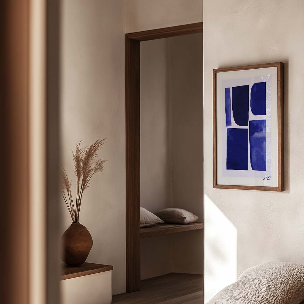 Moderne vægkunst med dybblå former i egetræsramme, vist i et roligt og naturligt interiør. Design af Kali Nuevo.