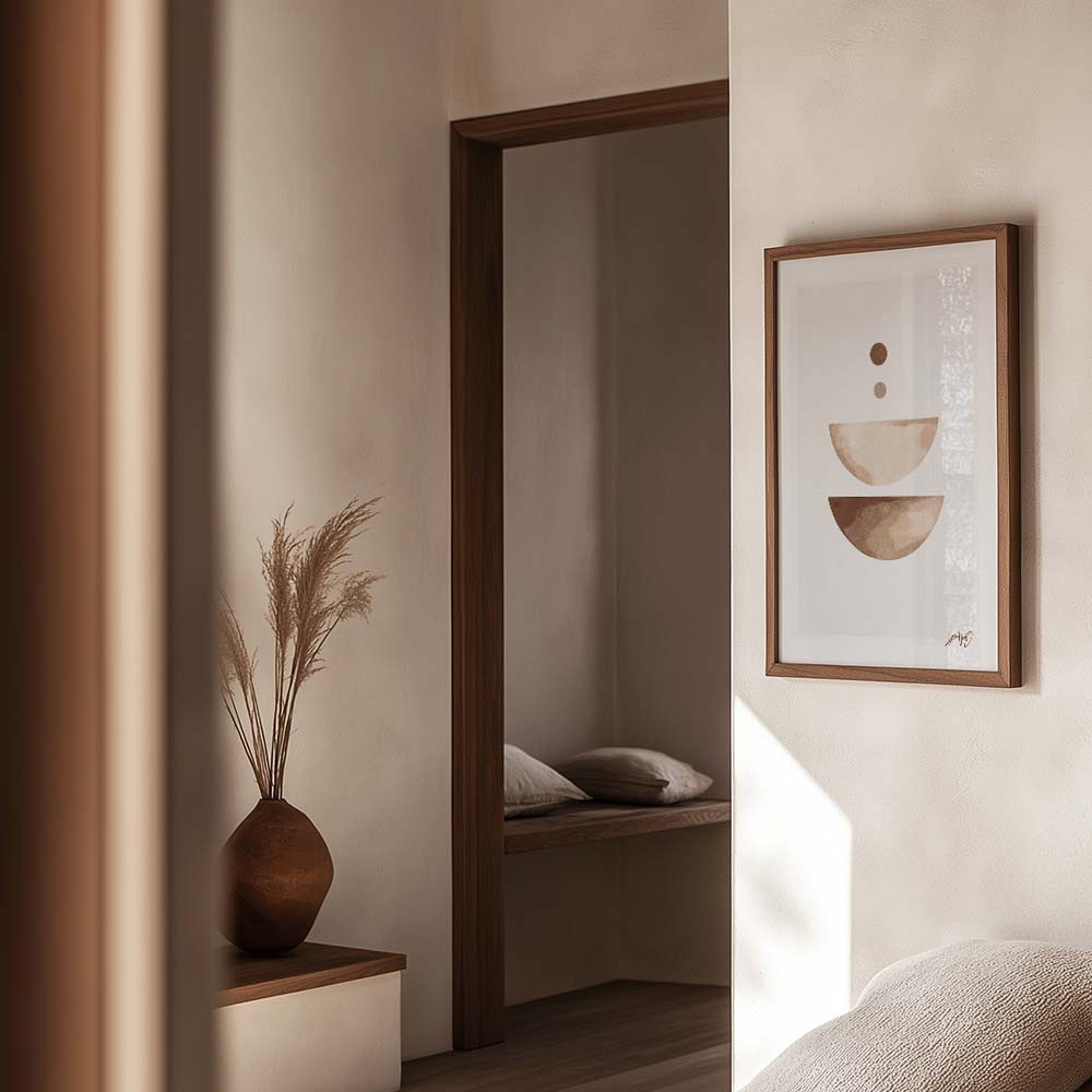 Kunstplakat med geometriske former i sandfarver, indrammet i egetræ og vist i et naturligt og roligt interiør. Design af Kali Nuevo.